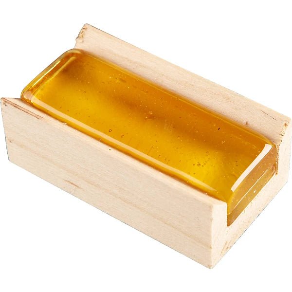 A rectangular block of AAA Woodframe Light Rosin rests in a small, open, unfinished wooden box.