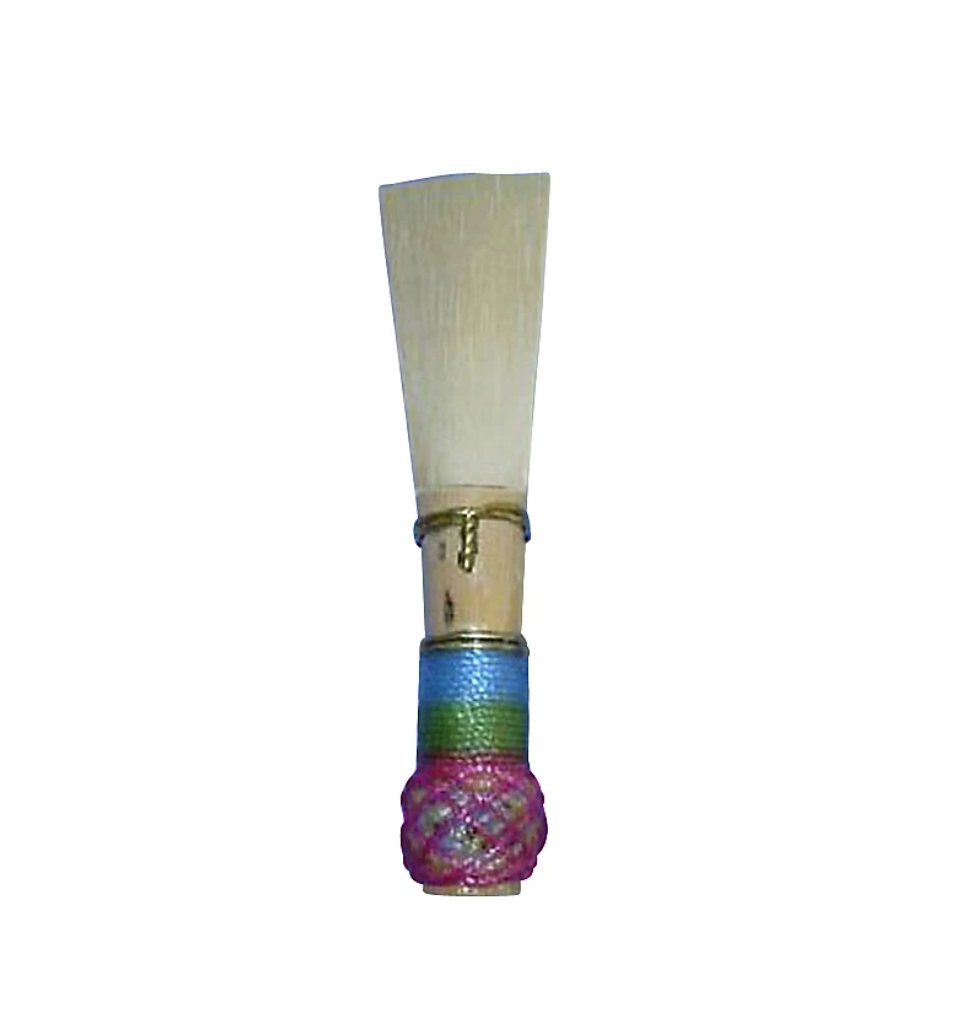 The Singin' Dog Bassoon Reed is a reliable, handmade reed featuring light tan cane, blue and green thread wrapping, and a decorative pink knot at the base, displayed on a white background.